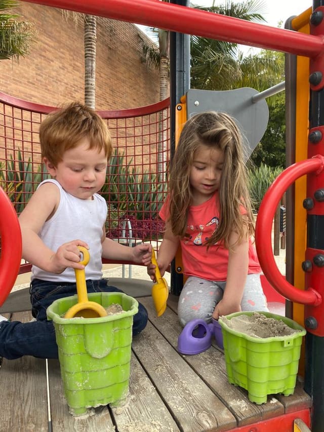 Two children playing side by side with buckets