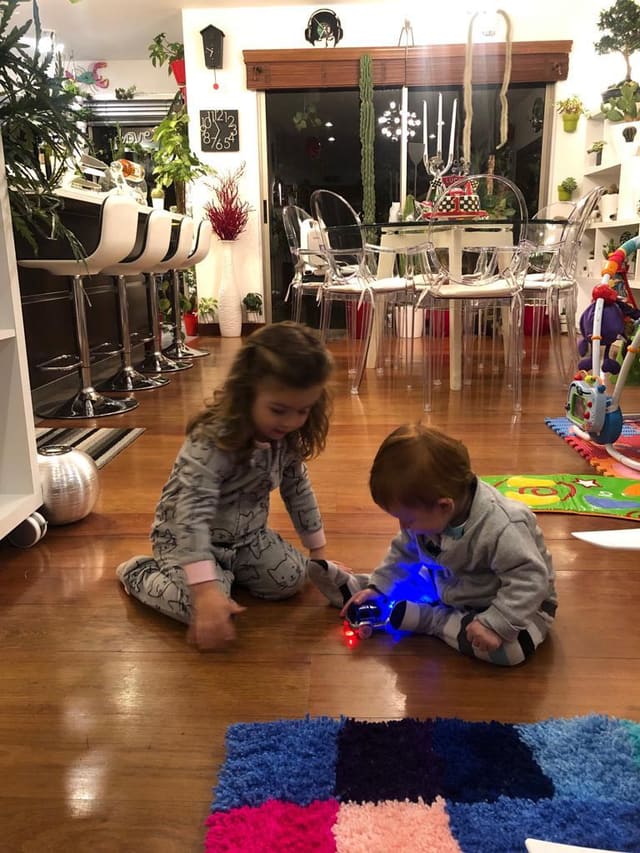 Two children sitting calmly on the floor at night with a glowing toy car between them